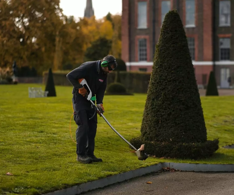 image of gardener mowing lawn by lawn mower