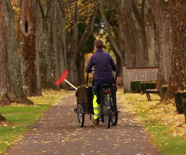 image of park cleaner cycling and cleaning in a park